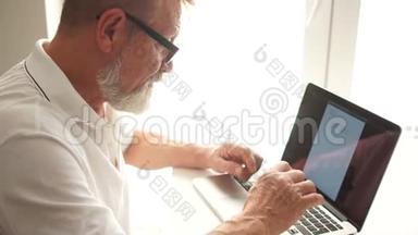 成熟的男人用笔记本电脑在家工作。 工作中的作家或科学家。 老年人用电脑写一封信